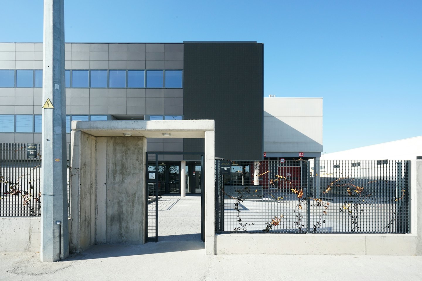 Modern industrial buildings with grey panels and reflective windows.