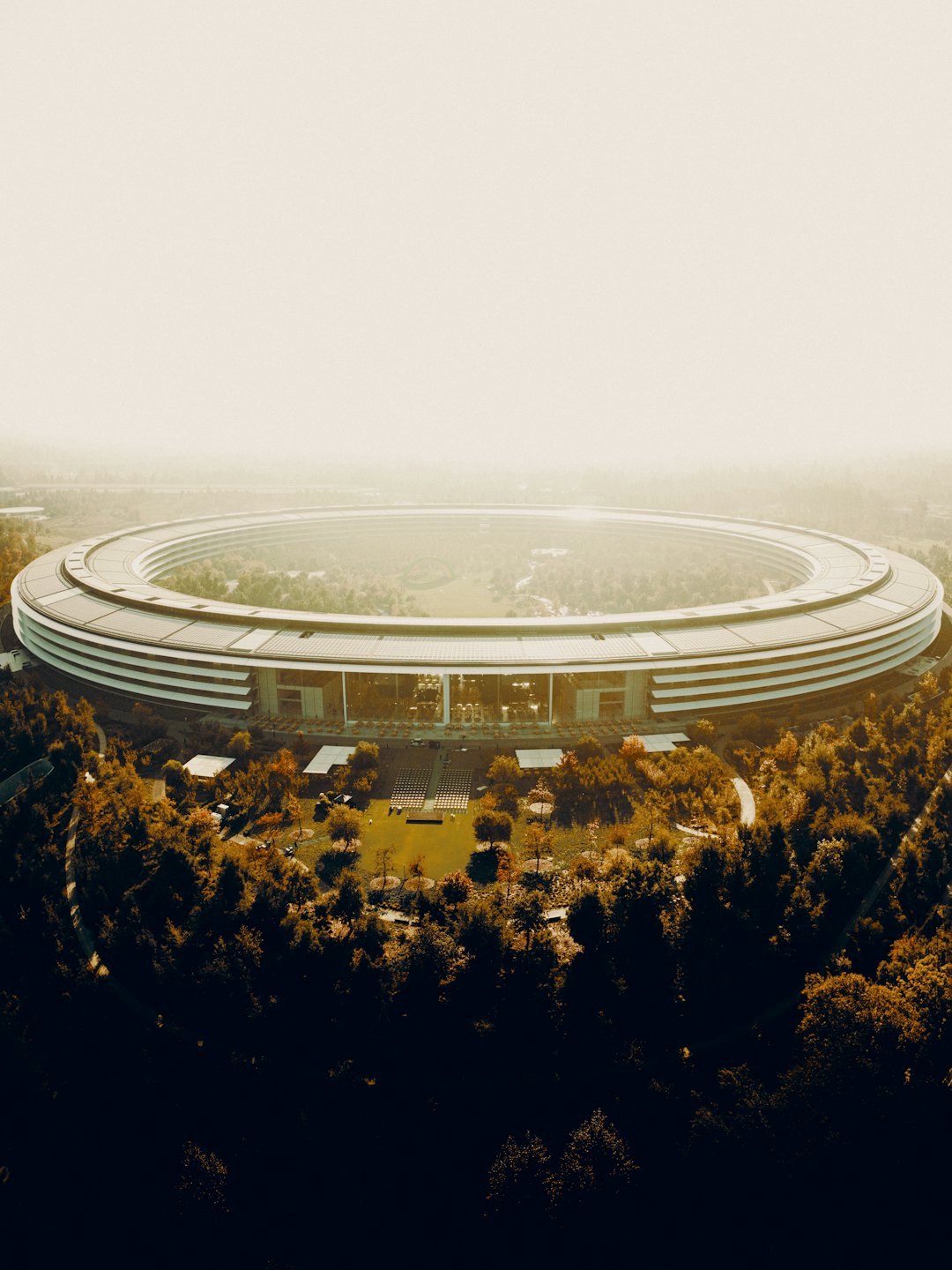 Modern circular corporate campus surrounded by green lawns and trees.